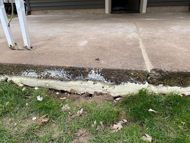 Close-up view of a sunken patio concrete slab edge showing the shifting and void gap in Thorp, WI.