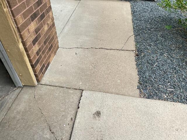 Cracked and uneven concrete sidewalk slabs requiring professional leveling near a home in Blaine, MN.