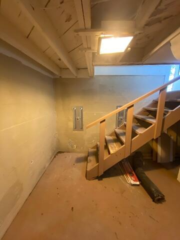 A clean basement corner showing two newly installed steel GeoLock wall anchor plates mounted on a foundation wall beneath a wooden staircase in Superior, WI.