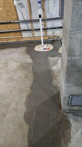 A newly installed SingleSafe sump pump system embedded into a concrete basement floor with clean PVC discharge lines in Cohasset, MN.