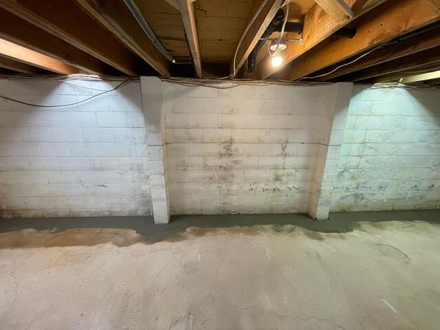 Wide-angle view of a clean cabin basement showing structural concrete block buttresses and a freshly concreted sub-floor drainage perimeter line in Cornucopia, WI.