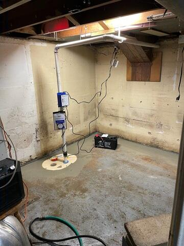 A heavy-duty DoubleSafe sump pump system with overhead PVC discharge lines installed on a freshly concreted basement floor perimeter in Gordon, WI.