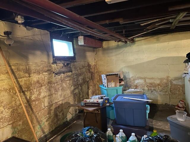Stained concrete block basement walls with efflorescence and moisture buildup before waterproofing repairs in Superior, WI.