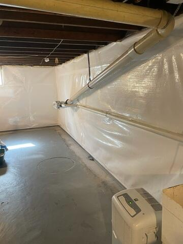 Clean white CleanSpace vapor barrier installed over basement walls alongside a new perimeter drainage system and a room dehumidifier near Washburn, WI.