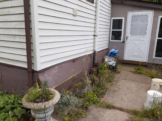 Cracked and uneven concrete patio slabs next to a home foundation before concrete repair service in Fairchild WI