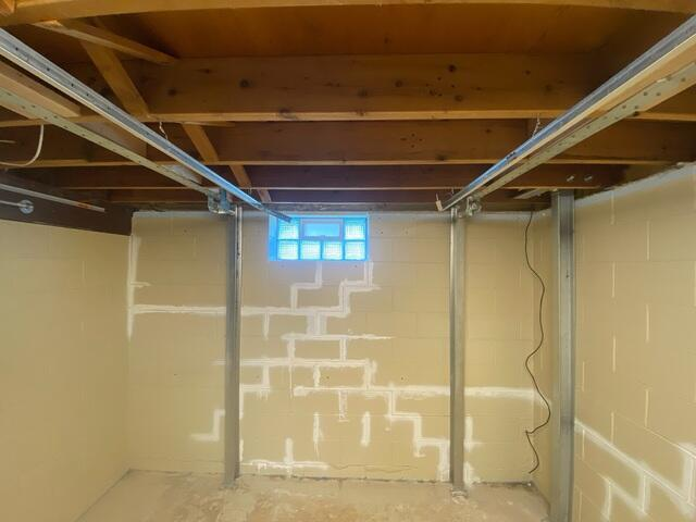 An interior basement view in Superior, WI showing a repaired block wall with white crack sealant lines and two vertical steel PowerBrace support columns.