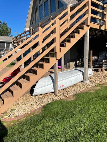 An exterior view of a multi-level wood residential deck and tall staircase structure with wood railings attached to a home in Shell Lake, WI.