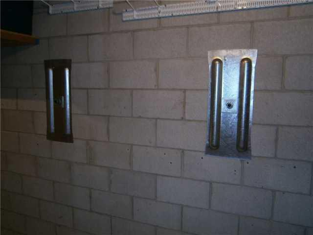 An immaculate basement view showing two heavy-duty galvanized steel GeoLock wall anchor plates cleanly mounted onto a concrete block foundation wall in River Falls, WI.