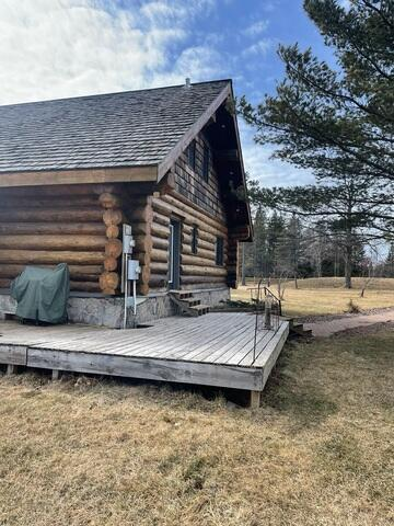 An exterior view of a rustic log lodge featuring a wide wooden plank deck and concrete block perimeter foundation in Holyoke, MN.