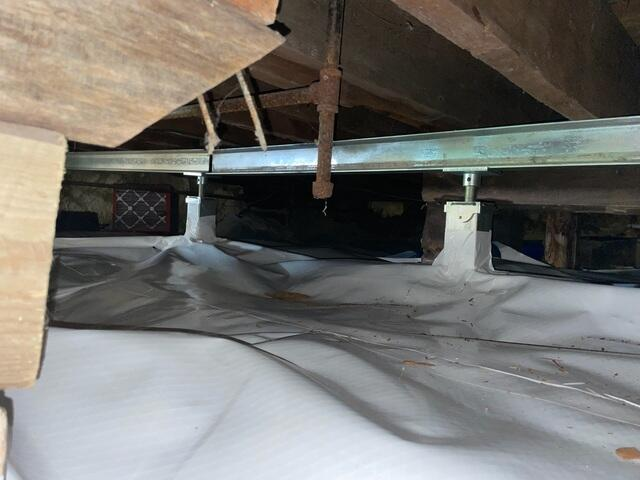 A perfectly completed crawl space in Ashland, WI showing a heavy galvanized steel SmartJack support column and horizontal steel beam mounted over a clean white CleanSpace vapor barrier.